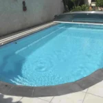 Margelles Silk gris Berg parfaitement adaptées aux courbes d’une piscine, réalisation Corbellini Carrelage Toulouse.