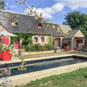 Piscine avec margelles en U, devant une maison typique en Bretagne, design extérieur élégant et contemporain.