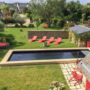 Vue du dessus d’une piscine avec margelles en L en Bretagne, design extérieur moderne et élégant.