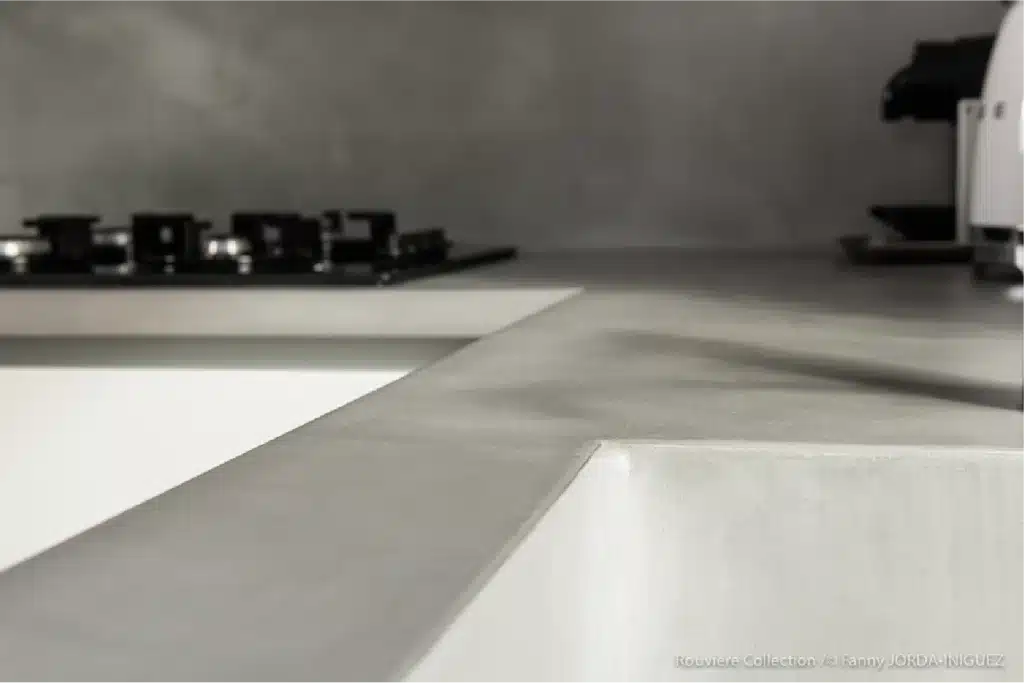 Angle plan de travail cuisine béton ciré gris clair Rouvière Collection, zoom finition élégante près plaque cuisson gaz, style intemporel moderne