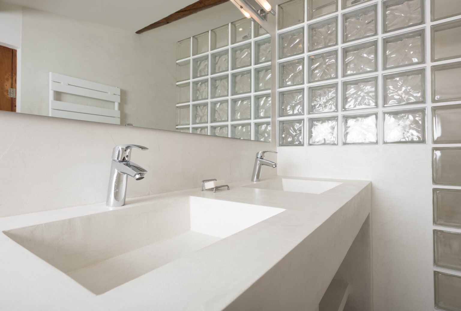 Mobilier de salle de bain en béton ciré avec paroi de douche en briques de verre, style moderne et épuré