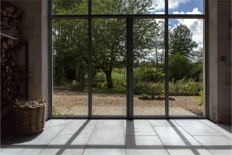 Carrelage gris bouchardé intérieur Rouvière Collection, style moderne industriel, grande véranda avec baie vitrée, design contemporain