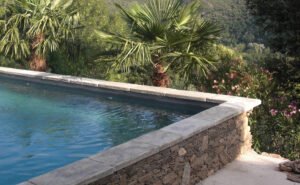 Piscine entourée de nature avec margelle Bourgeoise Uzès vieillie Rouvière Collection, béton décoratif résistant et esthétique pour aménagements extérieurs authentiques