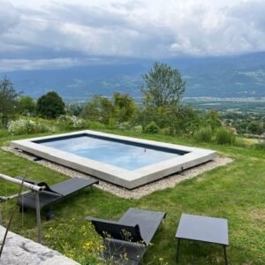 Bassin dans jardin de pelouse avec panorama spectaculaire, margelle L Manoir 56,5×100 R20 Gris Perl Rouvière Collection, béton décoratif résistant pour aménagements extérieurs
