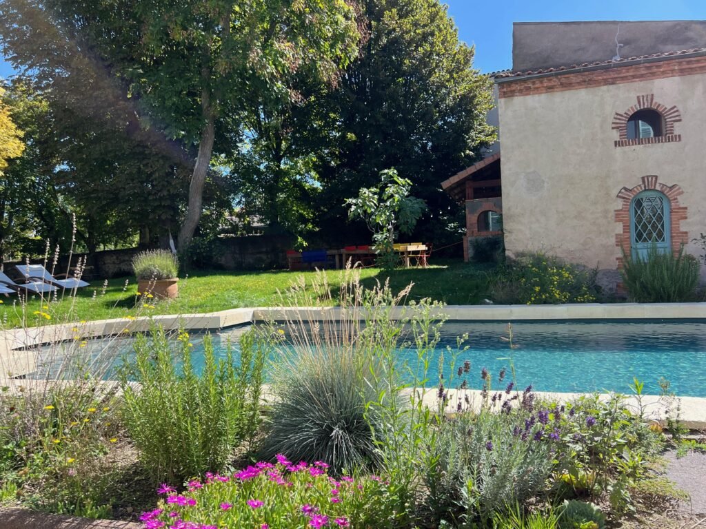 Piscine avec escalier roman et margelles en forme de L aspect pierre vieillie