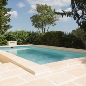 Piscine avec margelles en U Bourgeoise Rouvière Collection sur terrain en pente, béton décoratif aspect pierre pour aménagement extérieur durable