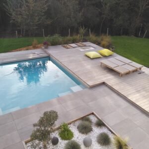 Margelle grésée grandes dimensions bordant une piscine avec plage bois et béton